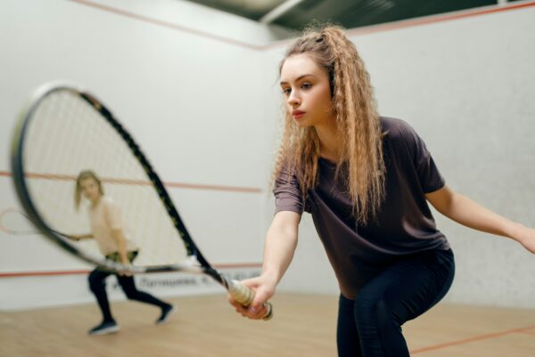 Two players with squash racket playing on court